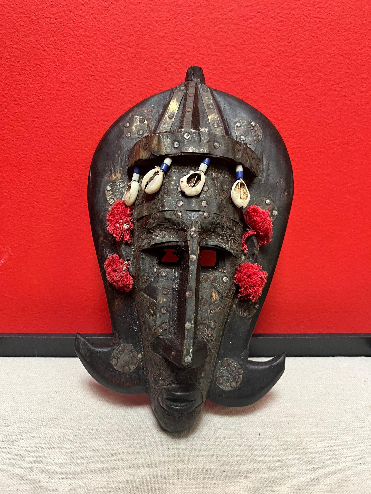 A 10 inch African mask with metal and puka shells   very decorative and old