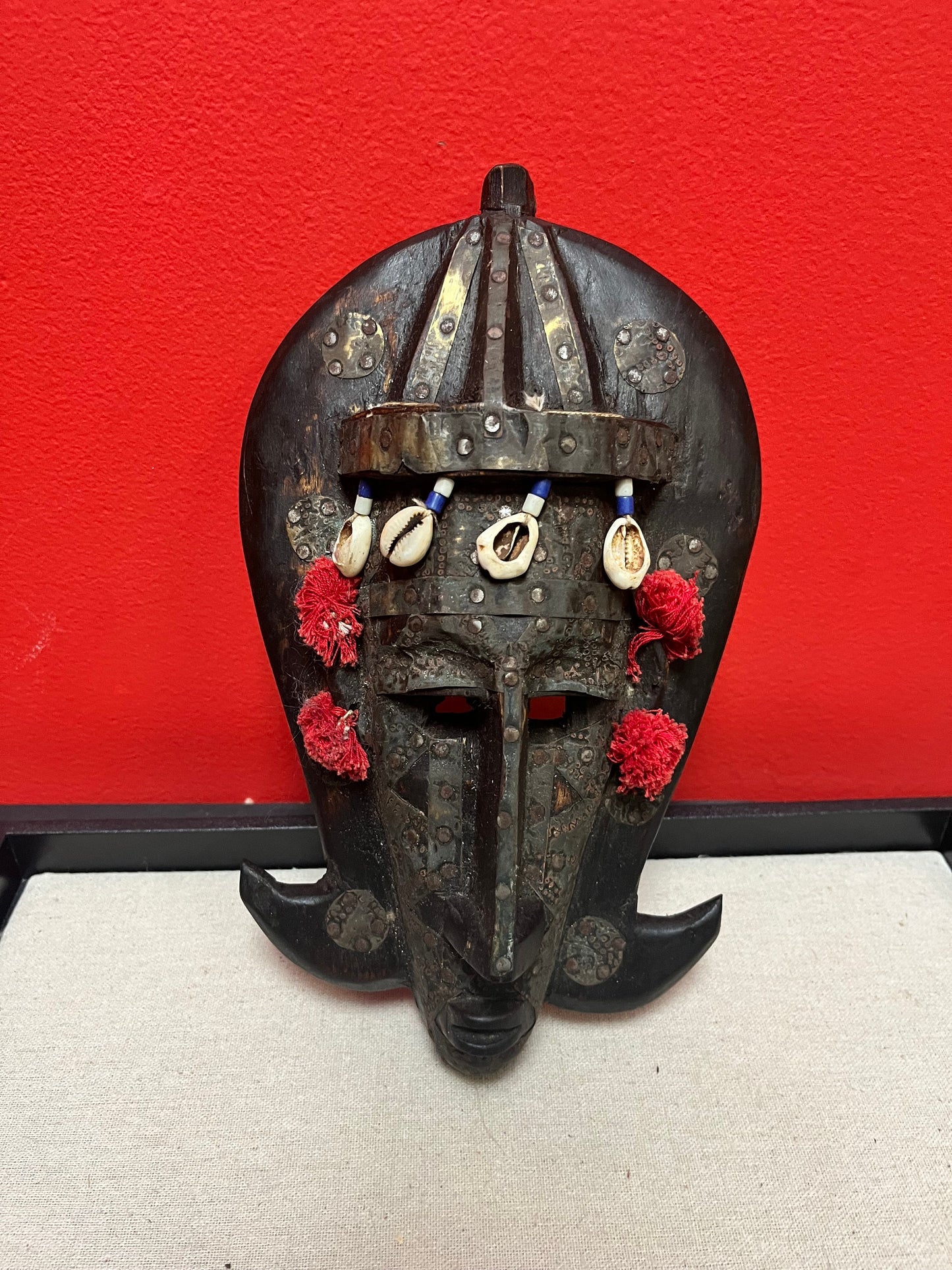 A 10 inch African mask with metal and puka shells   very decorative and old